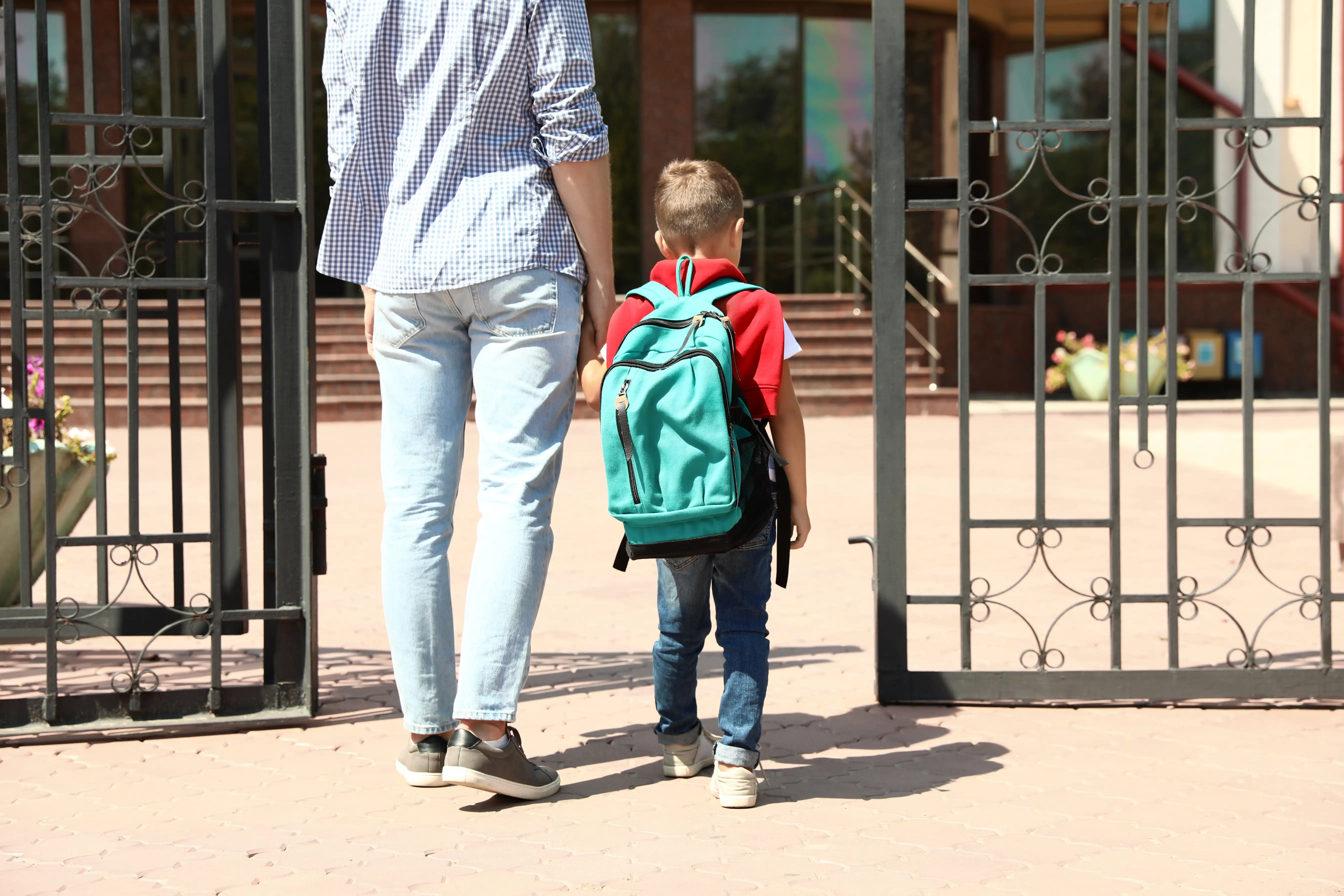 Ein Schulkind wird morgens zum Schultor begleitet